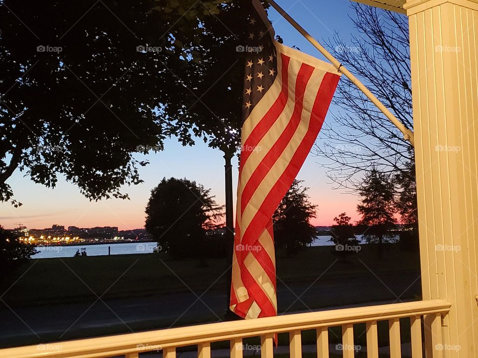 the American flag proudly displayed from the porch at sunset
