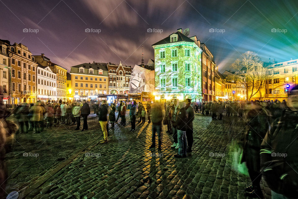 Festival of lights in the city. People walking in the night streets. Long exposure photo.