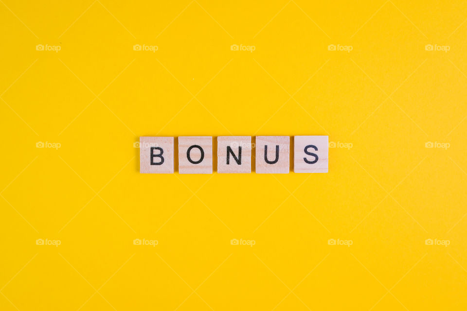 Word Bonus formed by wooden letters on orange background. Top view. Copy space