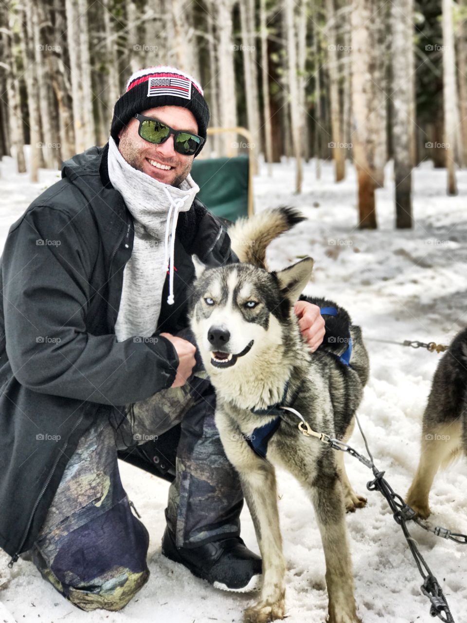 Young man with husky dog on snow in forest