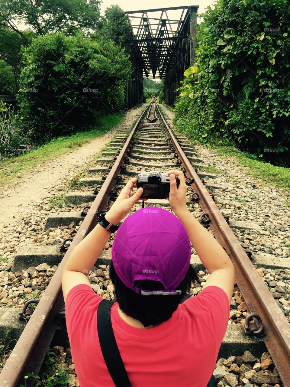Rear view of person taking photography on rail track