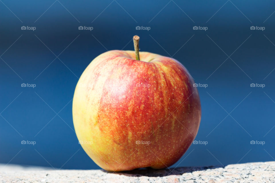 Colorful red yellow apple with blue ocean in the background 