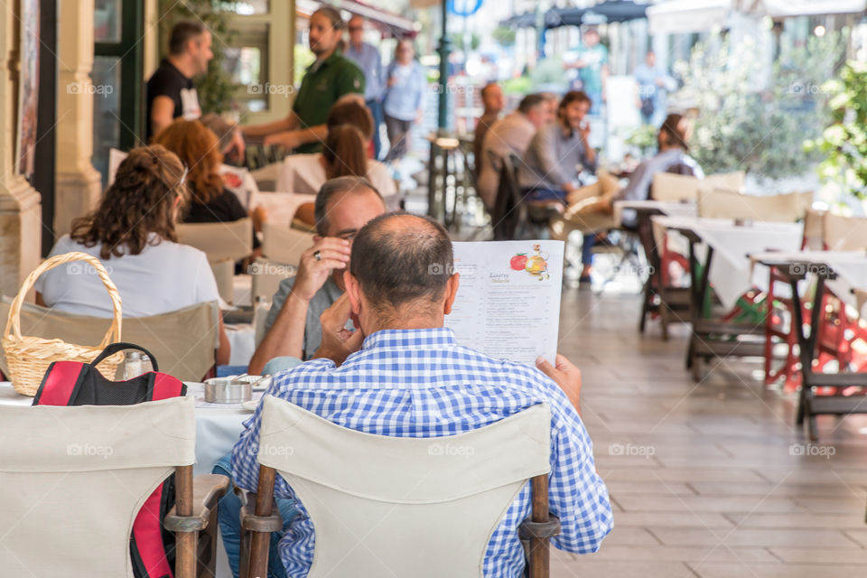 Friends Looking At Menu At An Outdoor Restaurant
