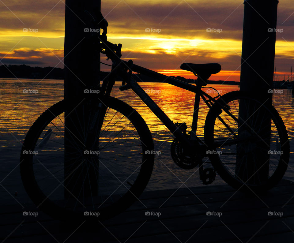 Silhouette of bicycle at beach during sunset