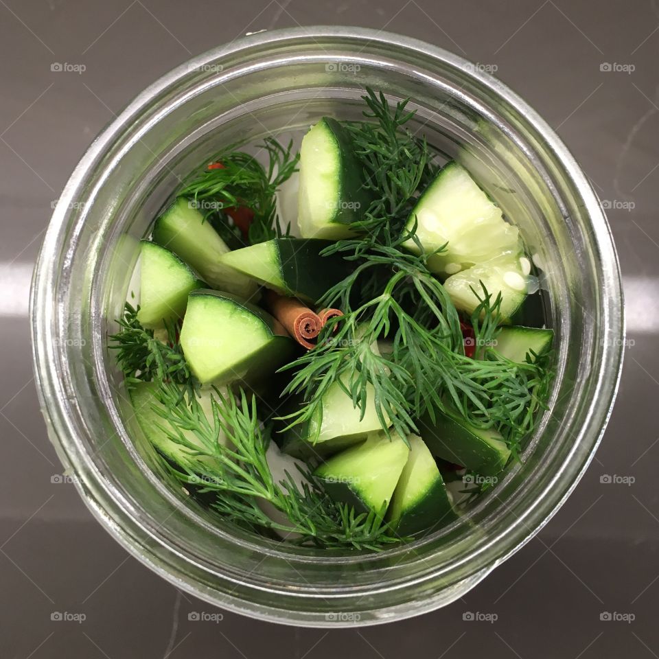 Jar of cucumbers, thyme, cinnamon and hot peppers ready to be pickled. 