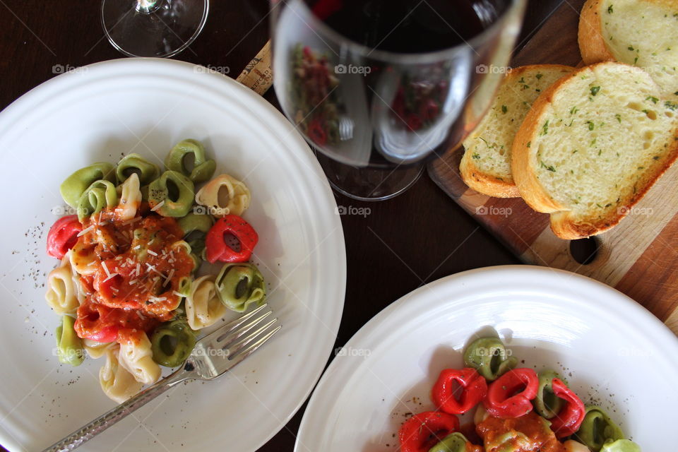 Italian inspired meal of tri-colored tortellini with red sauce and red wine.
