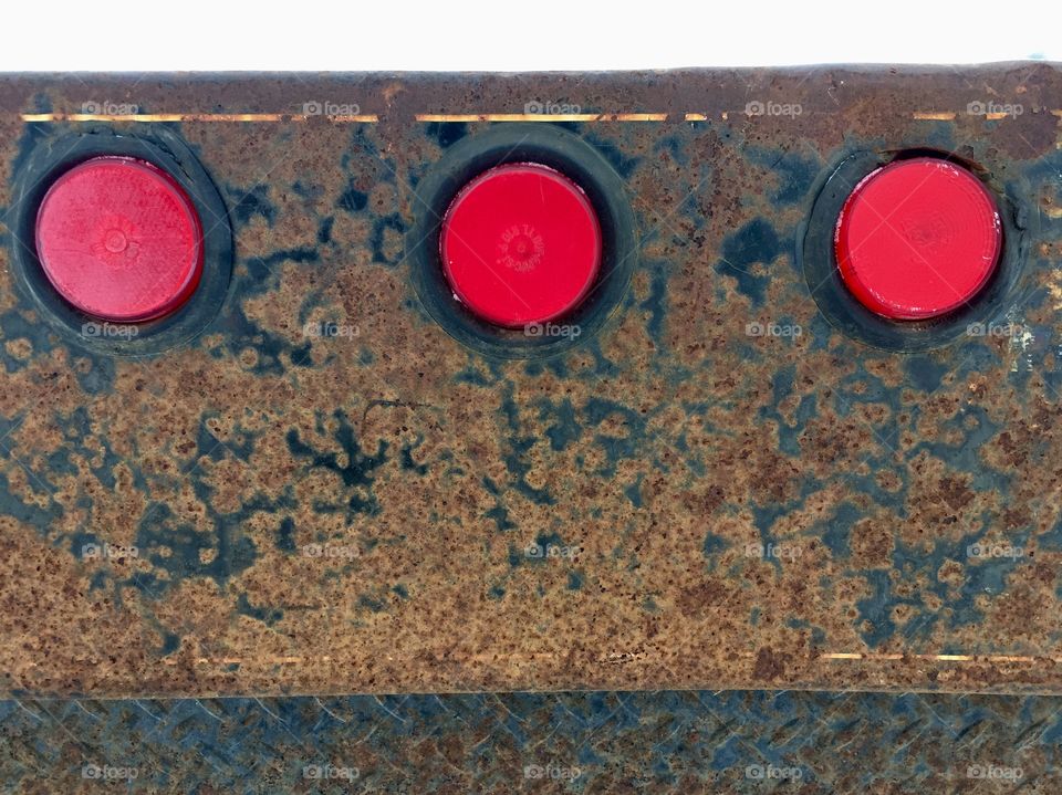 Closeup detail of three red taillights on a metal surface