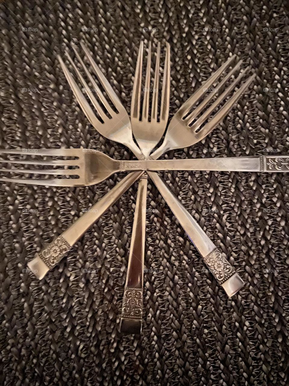 Four forks shaped into a shiny, multifaceted silver star set against the gray and silver background of a placemat. I can wish upon this star before I eat my breakfast! 