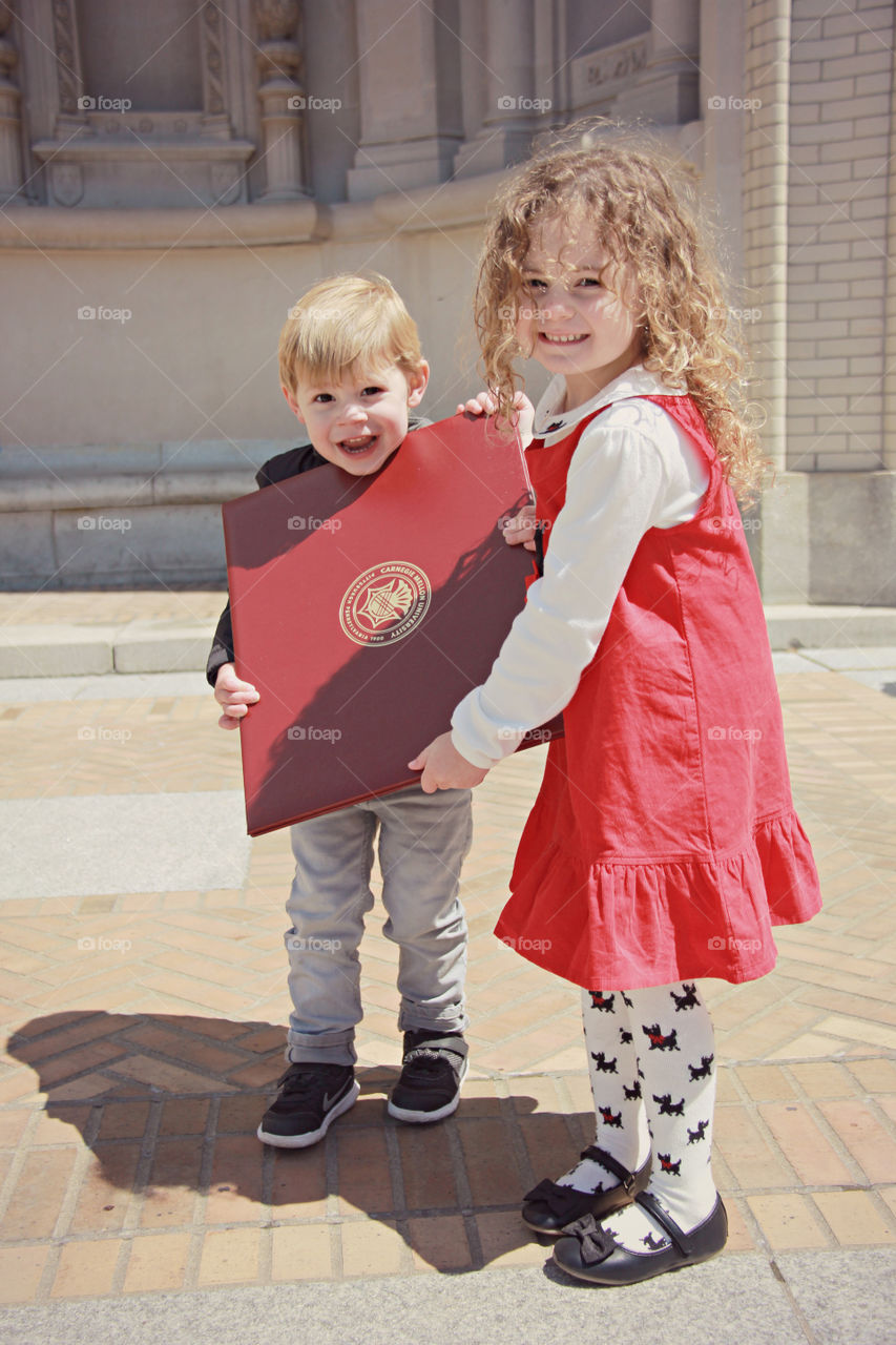 Two happy kids holding book