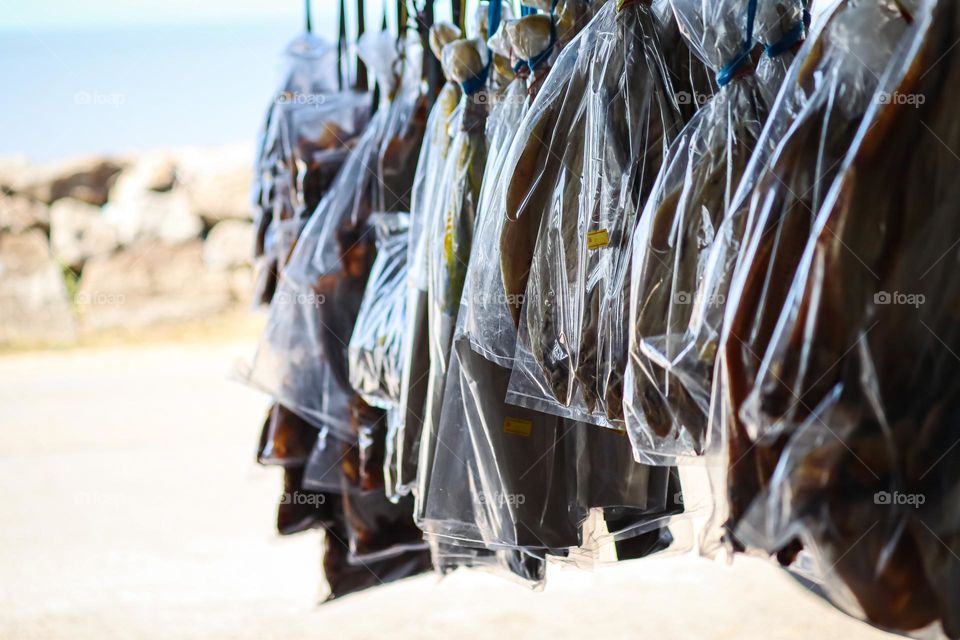 Selling salted dried fish on a local market. The product is hanged 