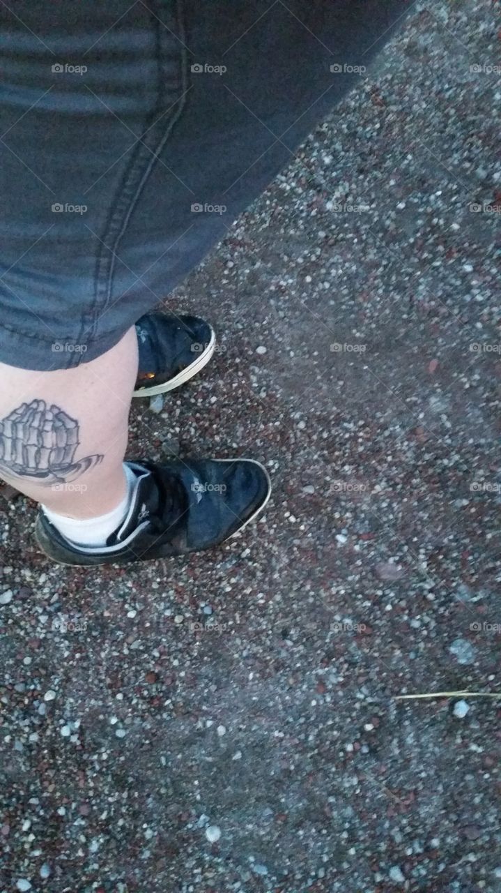 Standing on gravel, leg tattoo showing.