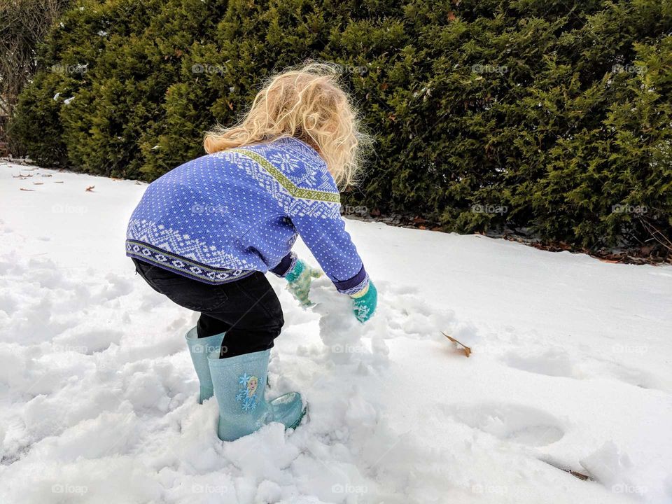 young girl building a snowman in the snow