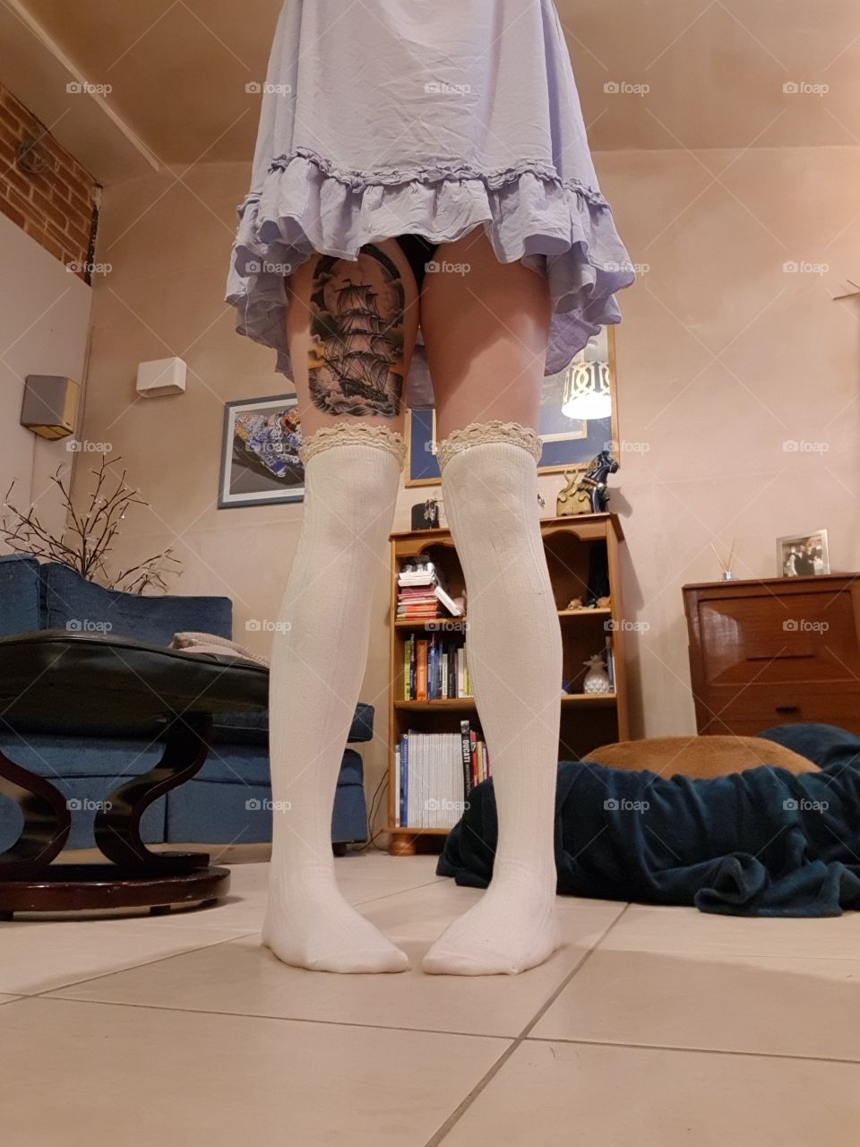 standing in a front room, not sure what to do. dont know what time day or night, thigh high socks on long tattooed legs wearing a nighty while the dog sleeps.