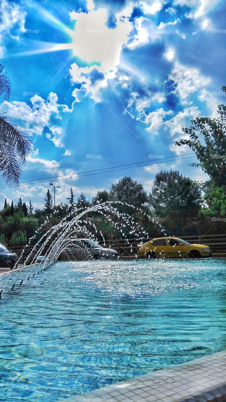 Noon on the streets of Athens,the sun plays games with a fountain and the trees...