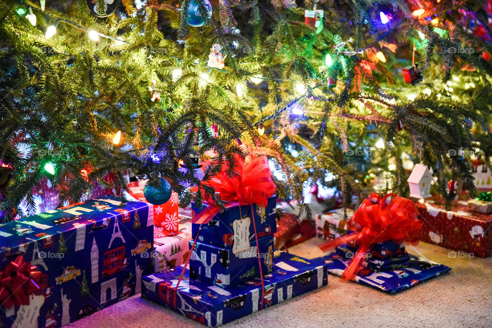 Wrapped presents with bows under a lit Christmas tree