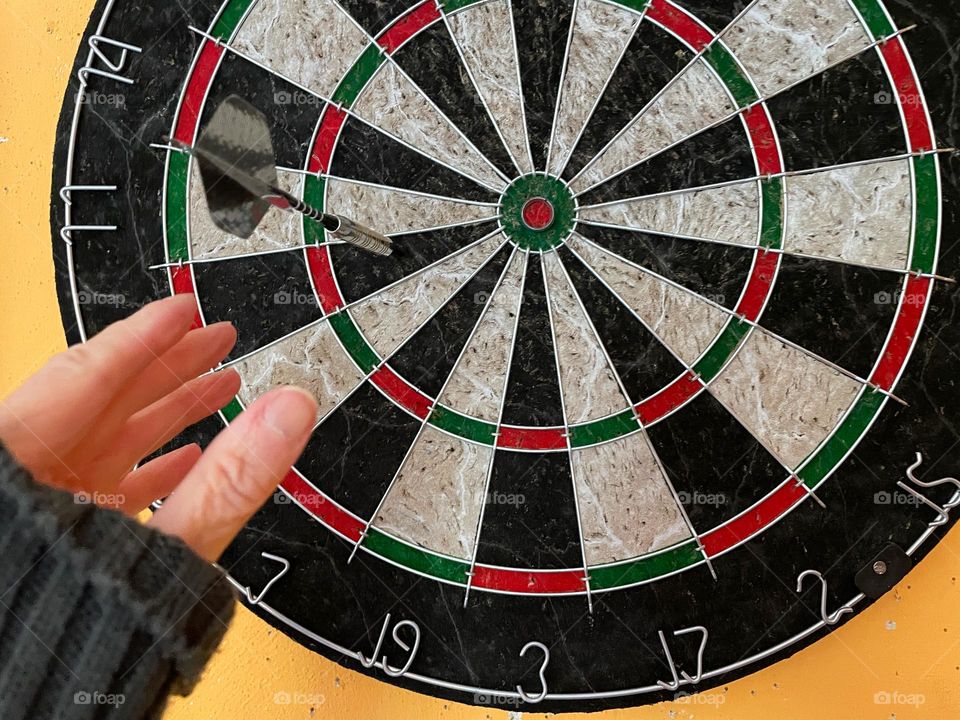 Close-up of a hand on a dart in a dartboard
