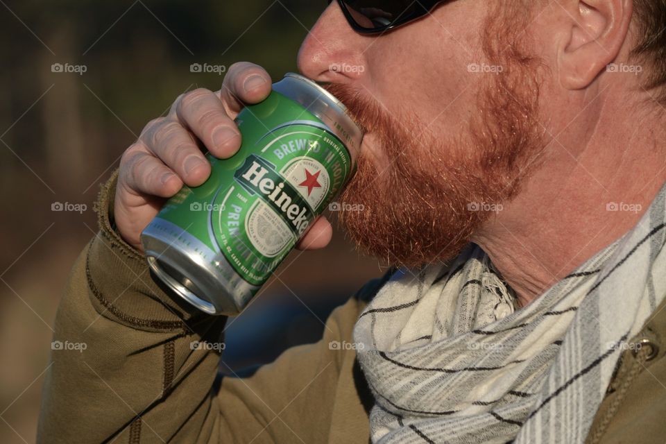 Man with Red Beard takes a sip of a Heineken Beer