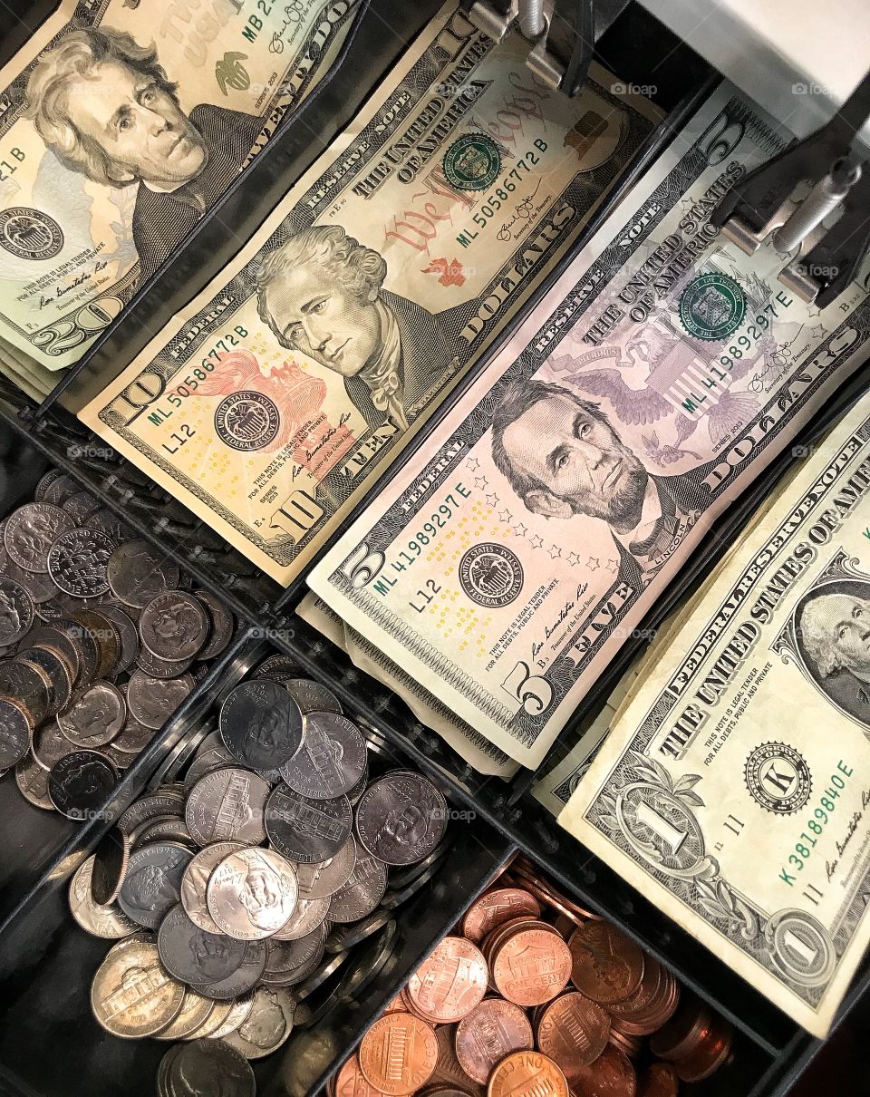 Close up of US currency showing bills and coins in a cashiers cash drawer