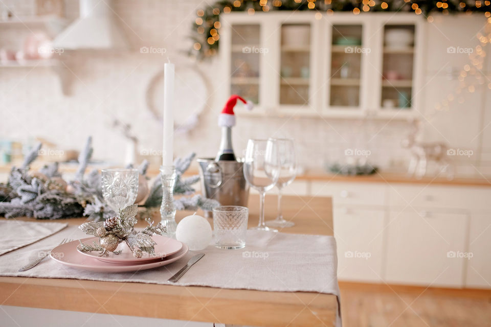 Festive winter cozy kitchen interior with garlands, decorations and gifts.  Christmas dinner at the decorated table.