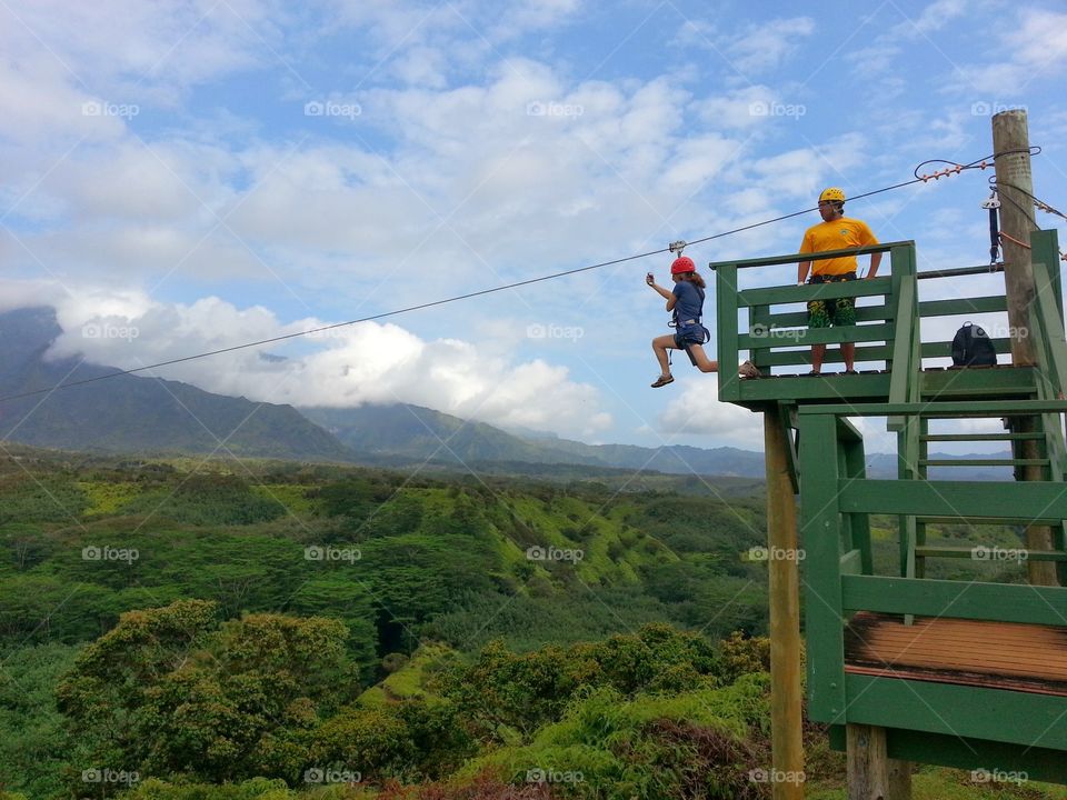 Zip lining action . Friend taking the first step to an awesome zip line experience. 