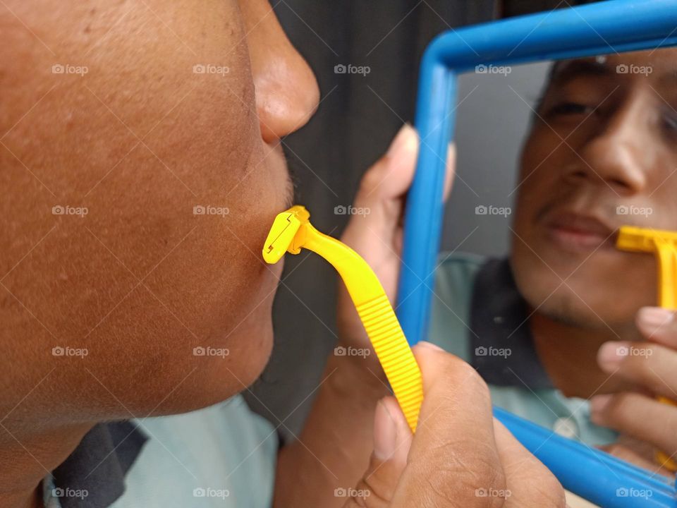 Man is shaving his mustache