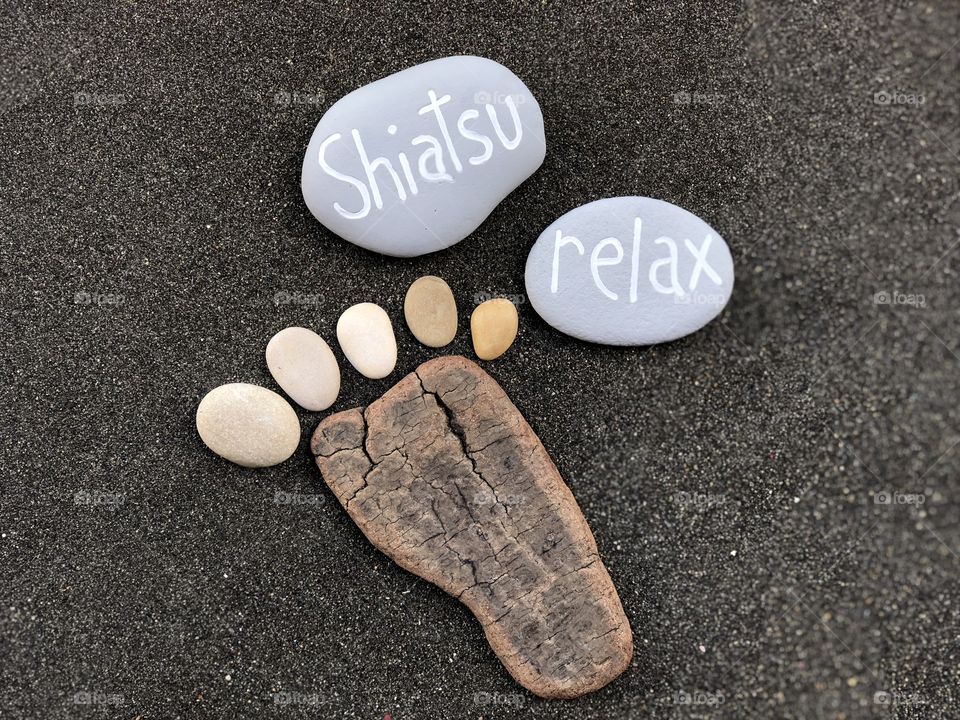 Shiatsu and relax concept with stones composition over black volcanic sand