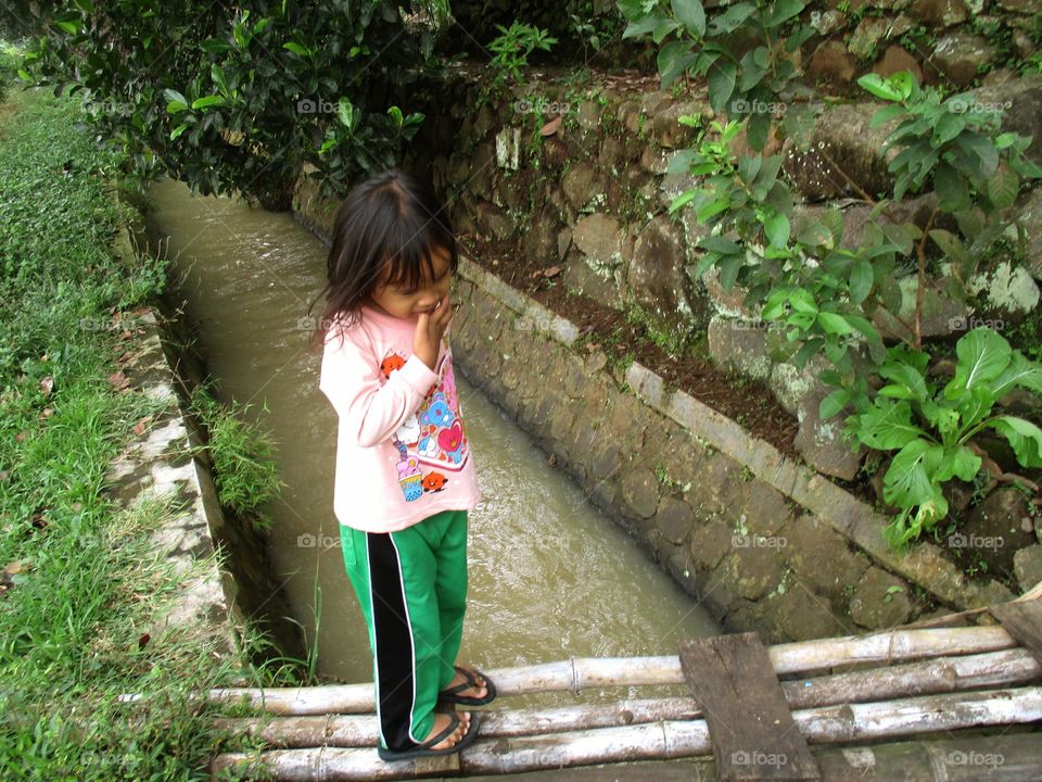 The little girl is on the bamboo bridge