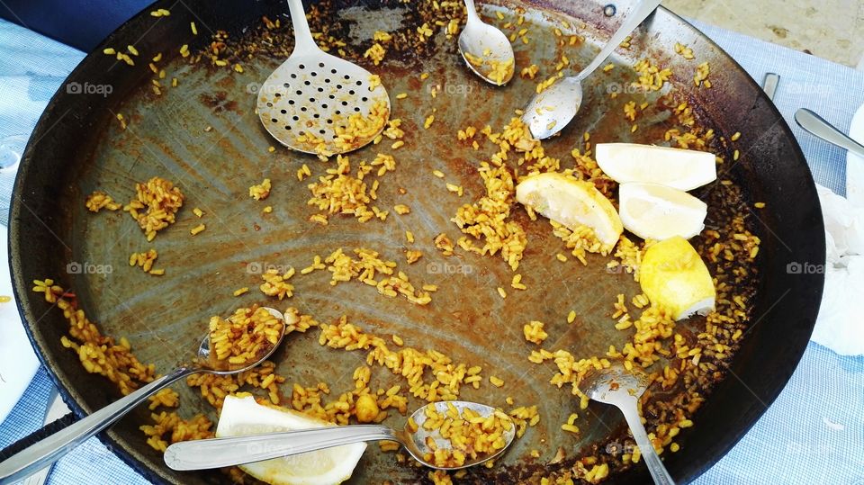 empty pan for cooking paella, full of spoons and lemons, a bit of rice and slotted spoon