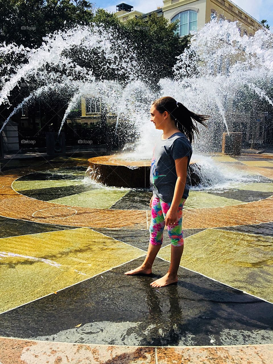 Girl playing in city fountain in Charleston