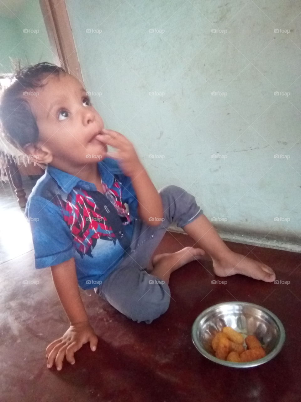 a little boy in relax mood eating kurkure.