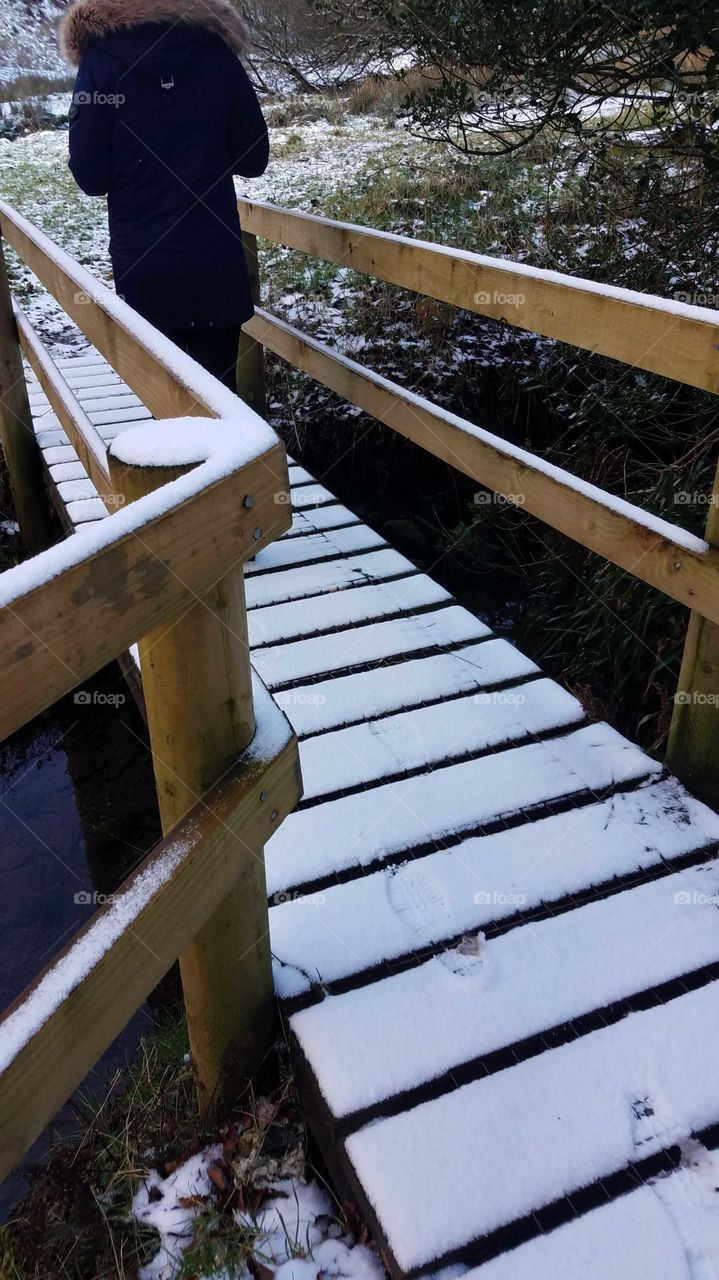 person walking on snowy bridge