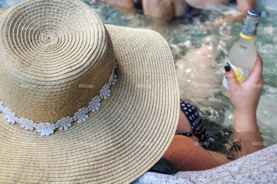 Girl relaxing in the hot tub with a drink 