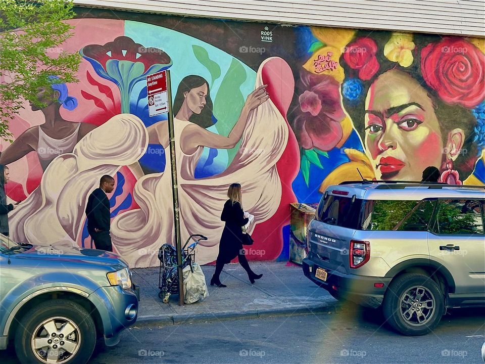 The club restaurant “La Lupe” is flourishing on “Jefferson St” off “Broadway” in “Bushwick”, Bklyn. Outside an almost a city block long mural celebrates the Latin culture with mulatto Hispanic dancers in flowing gowns. 2024. Hypnotic Productions