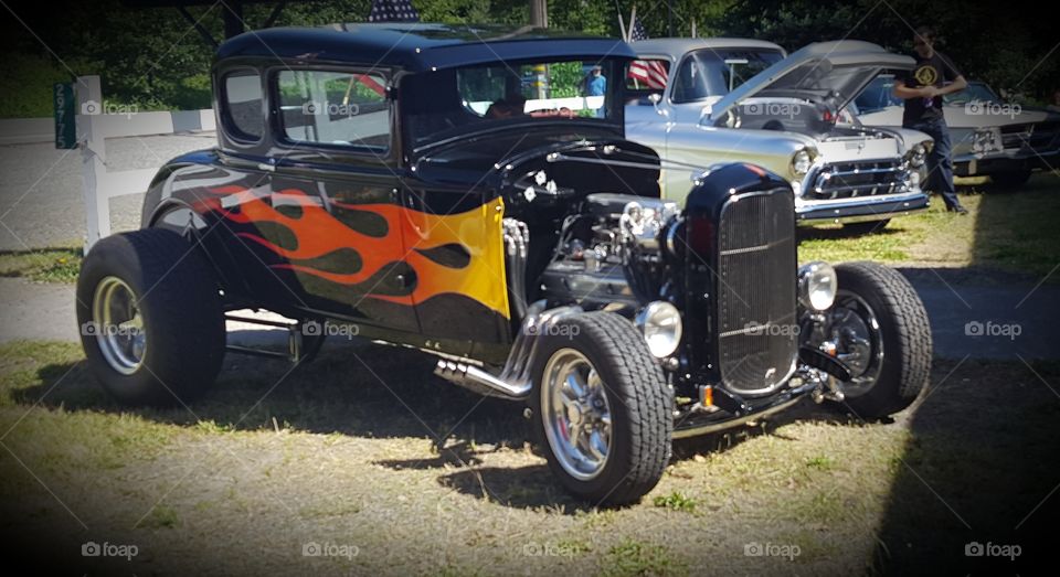 a classic hot rod at a car show with the classic flames on the sides