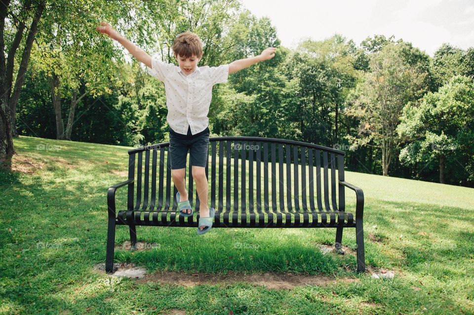 Boy jumping off bench.