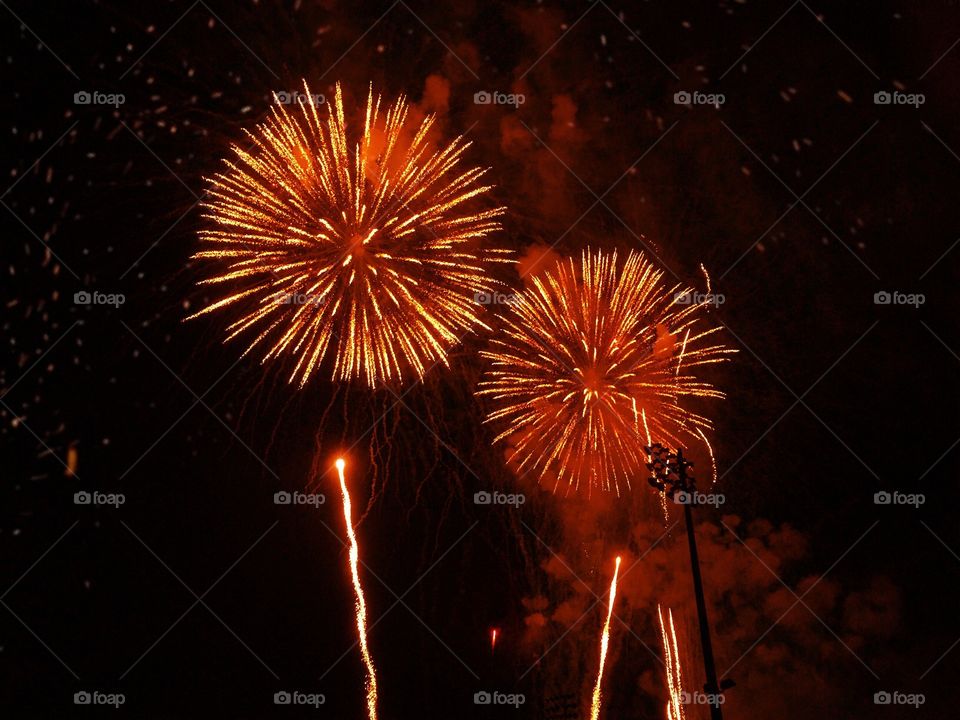 Beautiful hot orange fireworks light up the night sky.