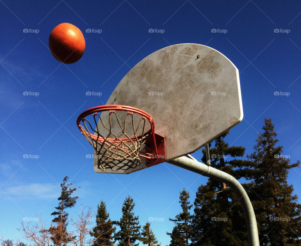 Orange basketball about to bounce off the backboard and swish through
