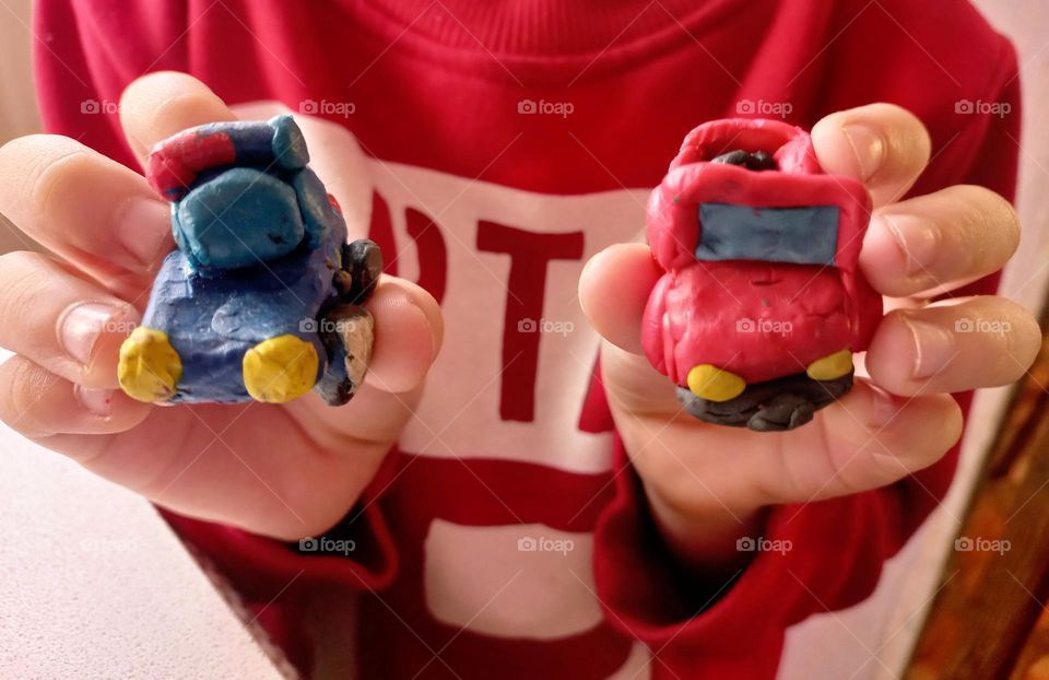 plasticine cars in the hands of a child.