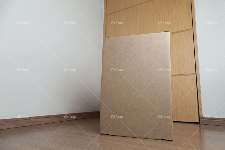 Cardboard box with order placed on the floor in an empty room with a neutral background. delivery concept. economy concept. business concept. shopping concept. copy space. Nobody