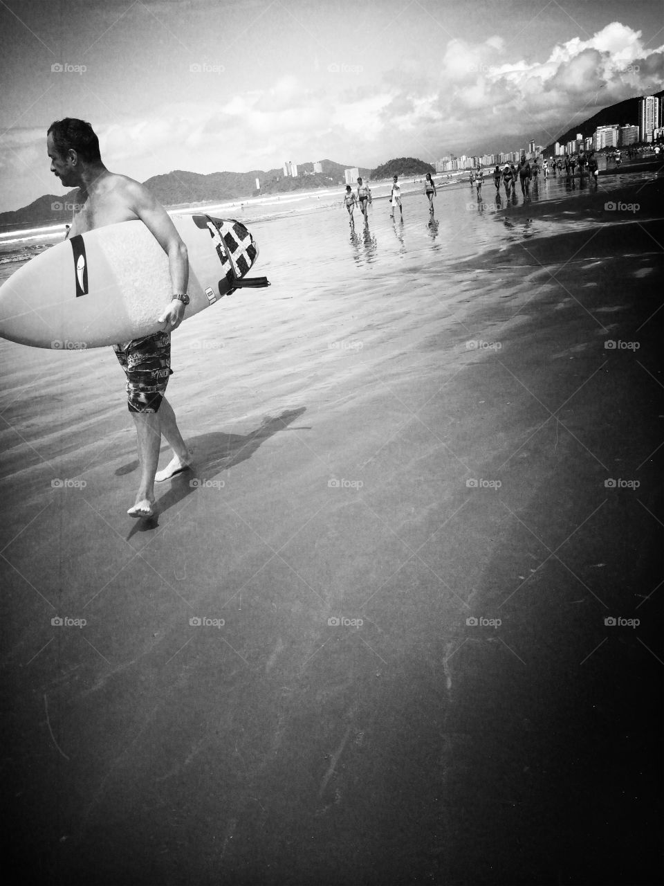 Man walking in a beach carrying a surfboard 