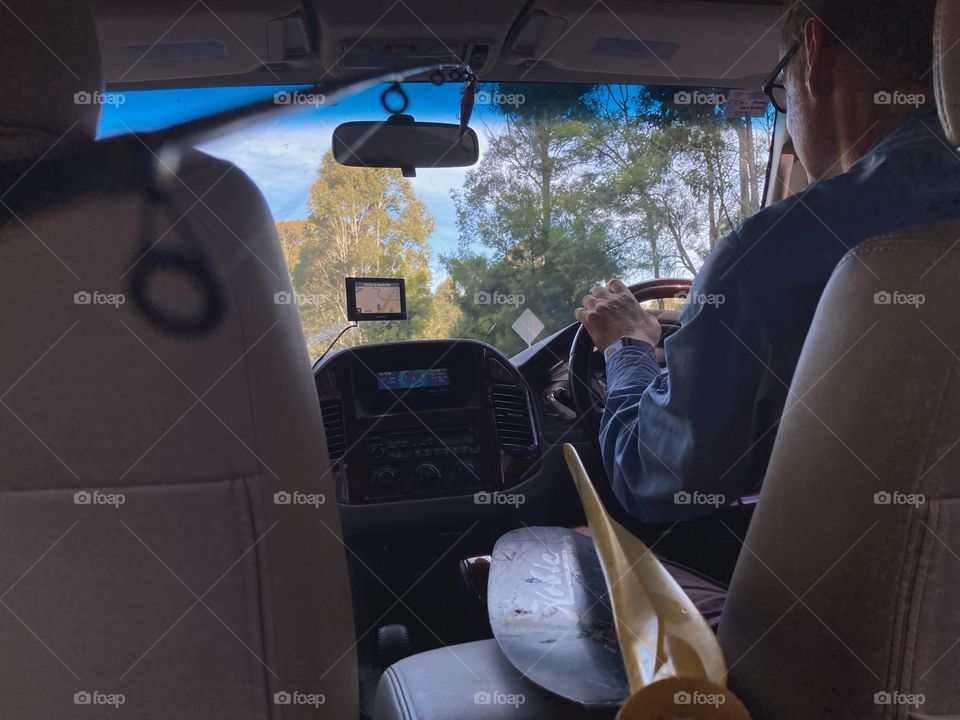 Backseat perspective: on the road at the coast in a car filled with kayaking and fishing gear.