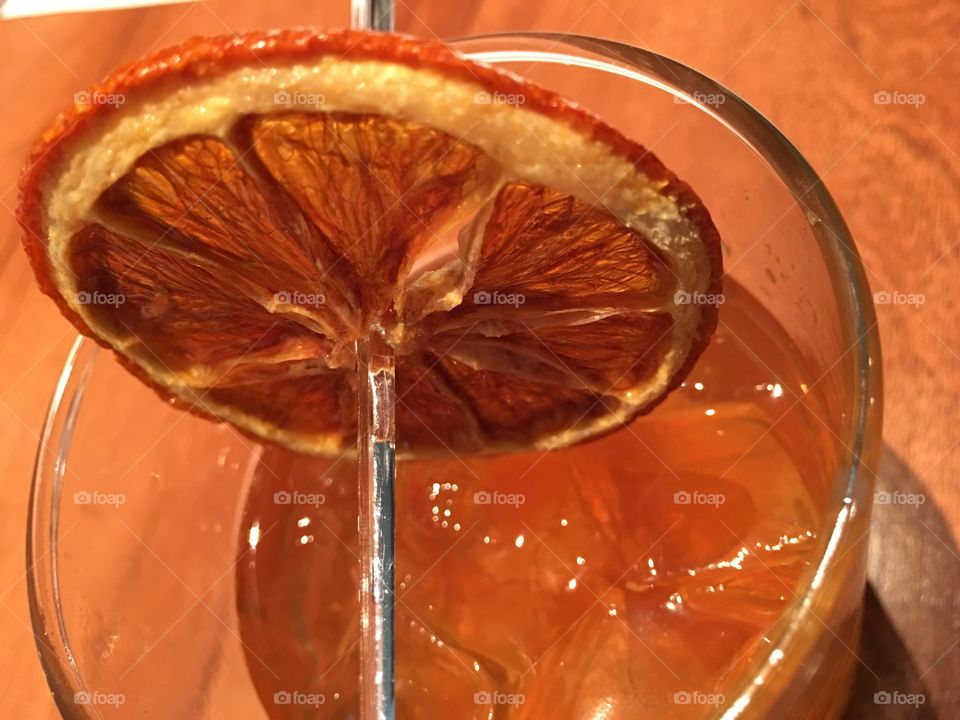 Orange slice flambe as a garnish on a mixed cocktail 