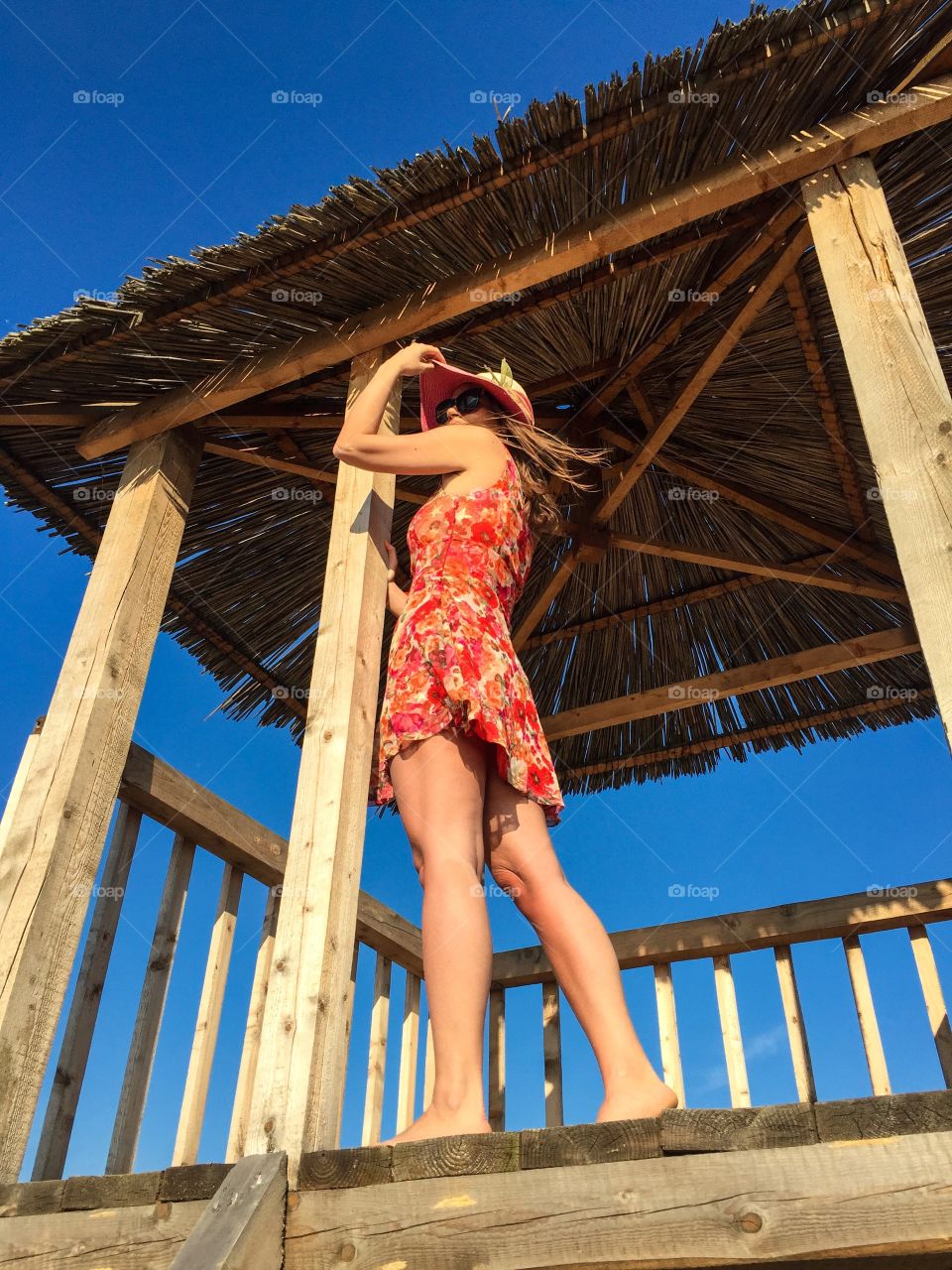 Pretty woman wearing summer dress and summer hat up in the lifeguard tower