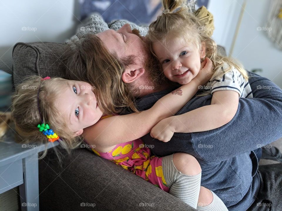 dad and daughters wrestle snuggling and laughing together, snuggling and piggy back ride with daddy, daddy daughter playtime