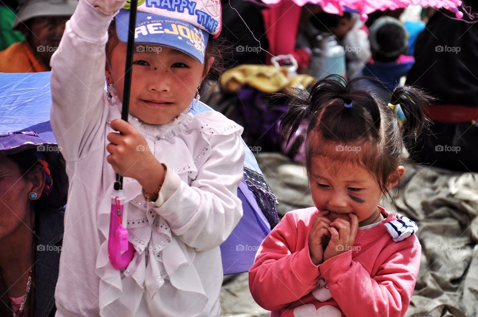 cute little girls under the sun umbrella in the yard of buddhist monastery in tibet