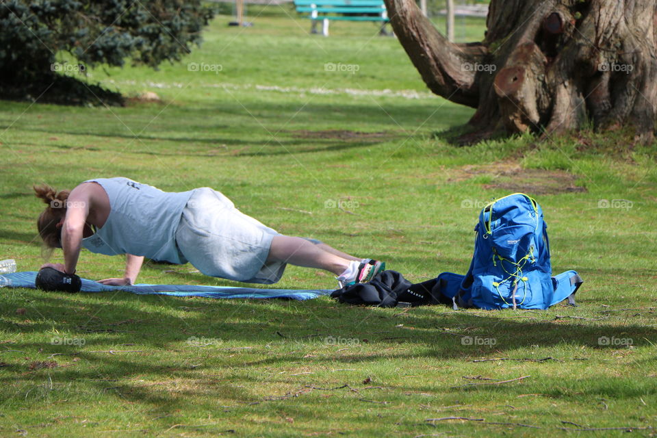 Man doing push-ups on his mat on the grass alone in the park ..stay fit in time of social distancing 😉