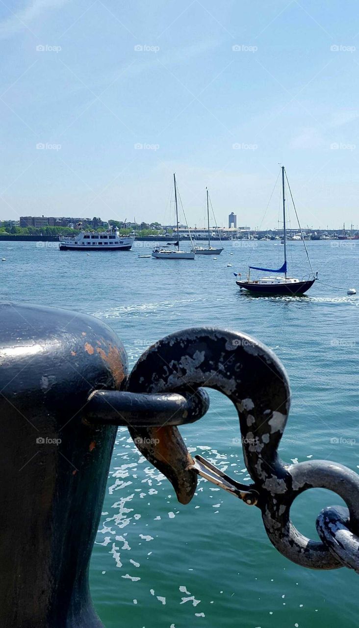 Gazing out from behind massive antique chains and hooks to ocean vessels setting sail from Boston Harbor.