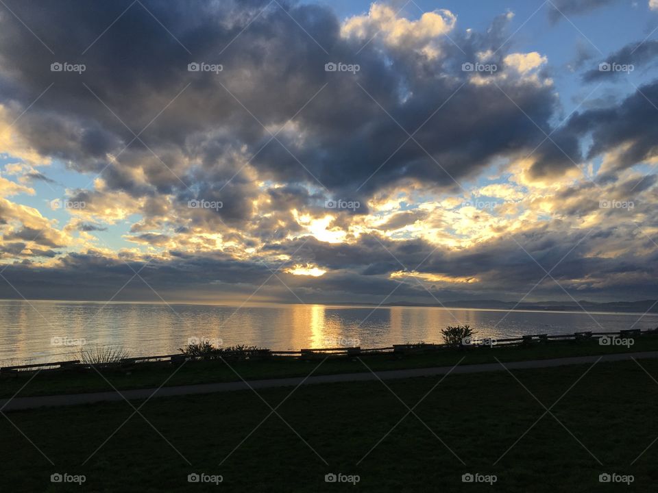 Dramatic sky with illuminated clouds , the sun trying to get through  and the calm ocean