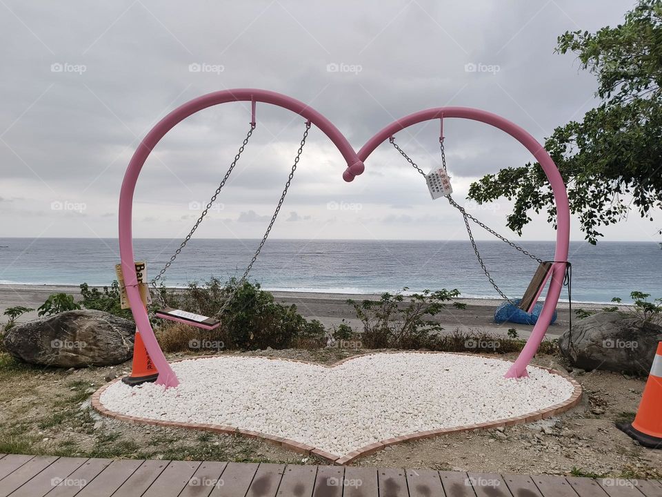 The blue seaside, the deactivated heart-shaped swing in autumn