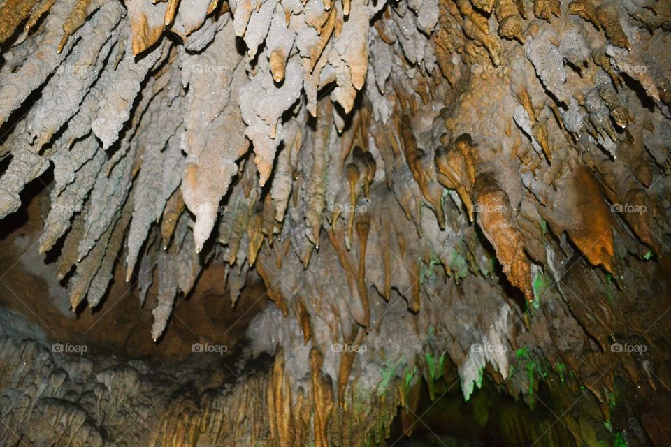 Beige and gray stalactite formations hanging from the top of an underground cave